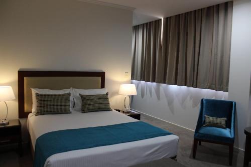a hotel room with a bed and a blue chair at Quality Hotel Regent Rockhampton in Rockhampton