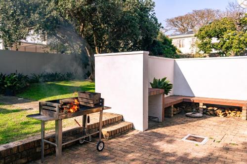 a barbecue grill in a backyard with a fence at Mountainside Family Beach House - Pet Friendly in Hermanus
