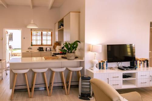a kitchen with a bar with stools and a tv at Mountainside Family Beach House - Pet Friendly in Hermanus