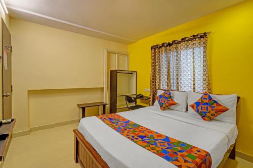 a bedroom with a bed with yellow walls and a window at FabHotel White Ridge in Hyderabad