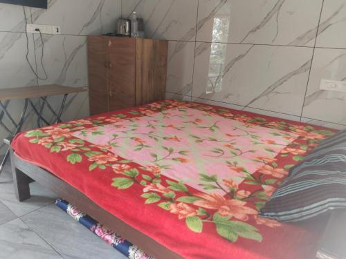 a bed with a red blanket with flowers on it at Nachiyar Hotel in Kanthalloor