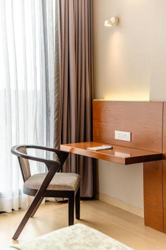 a desk and a chair next to a window at Hotel Tandav Ujjain in Ujjain