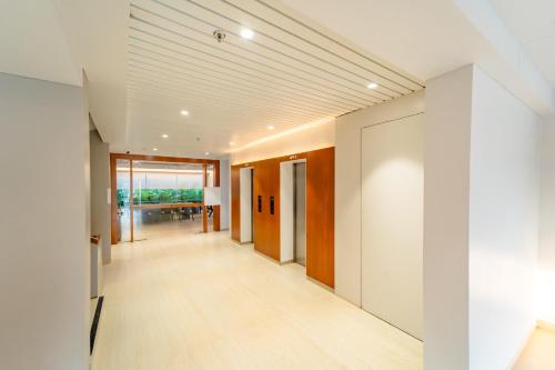 an empty hallway with white walls and wood floors at Hotel Tandav Ujjain in Ujjain