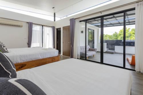 a bedroom with two beds and a sliding glass door at Laguna Park Phuket in Bang Tao Beach