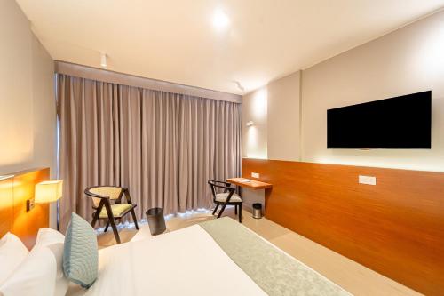 a hotel room with a bed and a flat screen tv at Hotel Tandav Ujjain in Ujjain