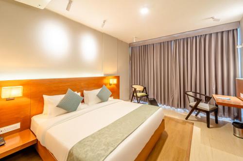 a hotel room with a bed and a desk at Hotel Tandav Ujjain in Ujjain