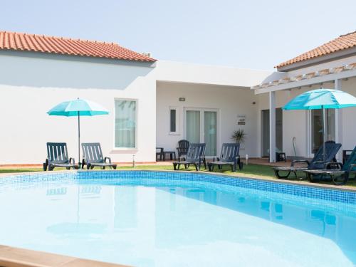 eine Villa mit einem Pool, Stühlen und Sonnenschirmen in der Unterkunft Tavira Monte in Tavira