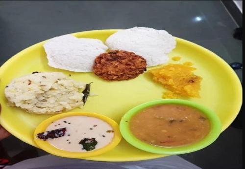 ein gelber Teller mit Reis und eine Schüssel Suppe in der Unterkunft De Asian Resort in Puducherry