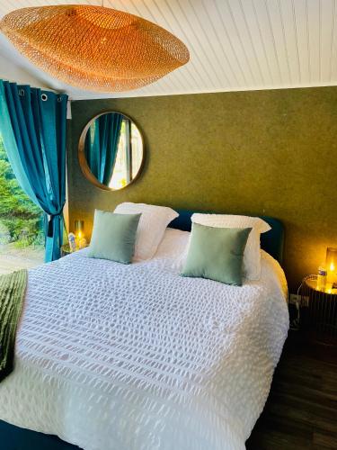 a bedroom with a large white bed with a mirror at Cottage, Lodge & Spa 64 in Prouilly
