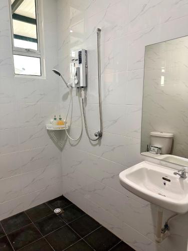 a white bathroom with a shower and a sink at MU Homestay in Simpang Ampat