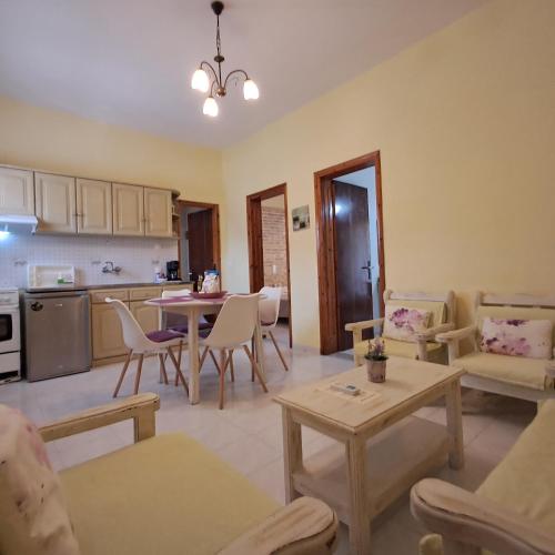 a living room with a table and chairs and a kitchen at Olga's Garden Apartments in Almiros Beach