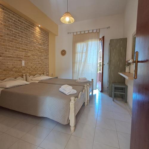 a bedroom with two beds and a brick wall at Olga's Garden Apartments in Almiros Beach