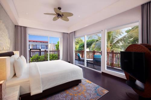 a bedroom with a bed and a balcony at Grand Mercure Bali Seminyak in Seminyak