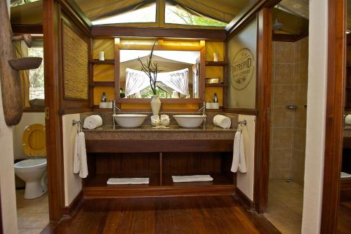 La salle de bains est pourvue de 2 lavabos et d'un miroir. dans l'établissement Mara Intrepids Tented Camp, à Talek