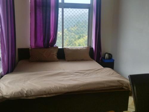 a bed in a room with a window with purple curtains at Sona Hotel and Restaurant By StayApart in Kanatal