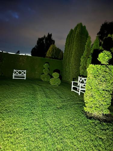 a green yard with a white fence and bushes at Brīdis Sev in Ķekava