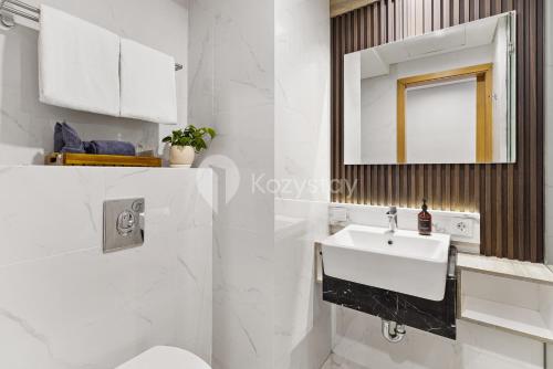 a white bathroom with a sink and a mirror at Caraya by Kozystay - Nusa Dua in Nusa Dua