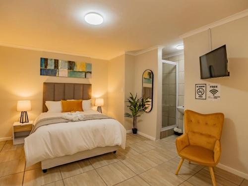 a bedroom with a bed and a chair and a television at Olive Grove Bed & Breakfast in Kraaifontein