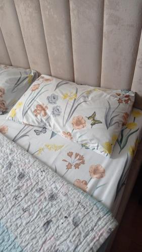 a bed with a floral comforter and two pillows at Квартира in Aktobe