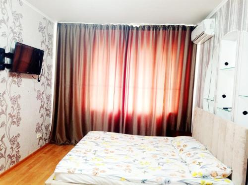 a bedroom with a bed in front of a window at Квартира in Aktobe