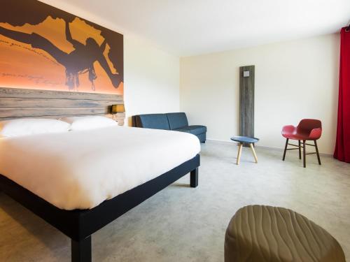 a bedroom with a bed and chairs in a room at Ibis Styles Sallanches Pays du Mont-Blanc in Sallanches