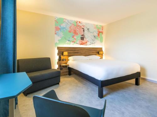 a bedroom with a bed and a couch and a chair at Ibis Styles Sallanches Pays du Mont-Blanc in Sallanches