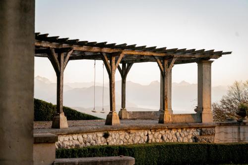 a wooden pergola with mountains in the background at Château des Avenieres in Cruseilles