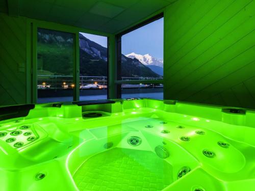 a green bath tub in a room with windows at Ibis Styles Sallanches Pays du Mont-Blanc in Sallanches