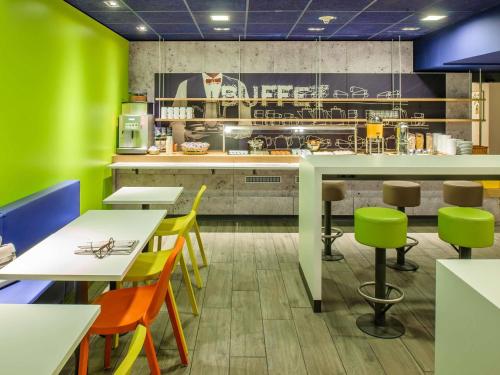 a restaurant with green walls and tables and chairs at ibis budget Divinopolis in Divinópolis