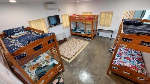 a room with three bunk beds and a television at Beach House, San Juan, La Union in San Juan