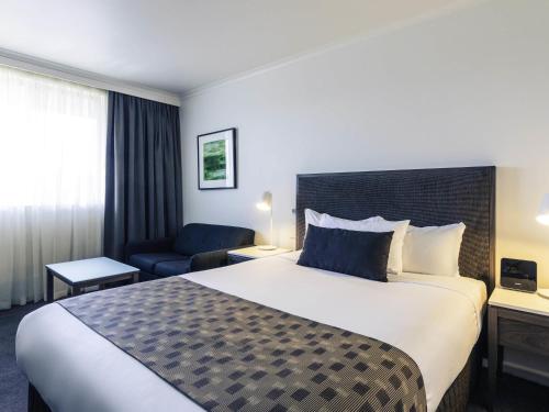 a hotel room with a large bed and a chair at Mercure Albury in Albury