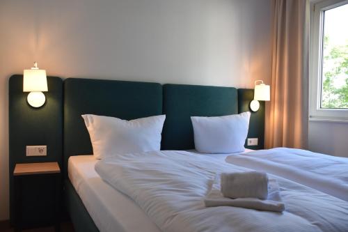 a large bed with a green headboard and white pillows at ARC Hotel in Halle an der Saale