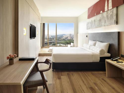 a hotel room with a bed and a desk and a window at ibis Kuala Lumpur City Centre in Kuala Lumpur