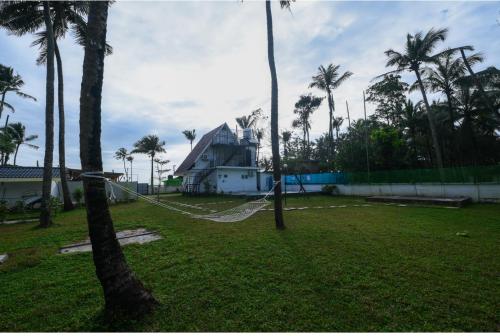 a yard with palm trees and a house at Nirvana-Vadanappally Beach Villa in Irimbranallūr
