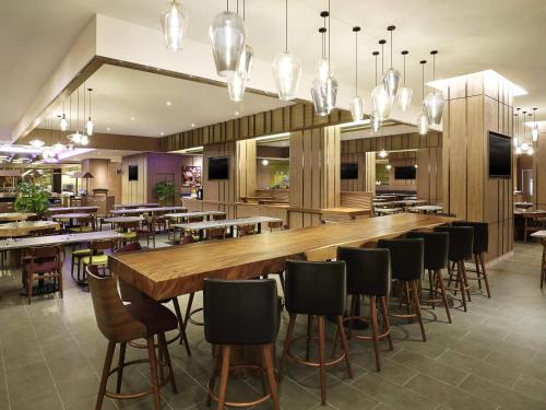 a restaurant with a long bar with chairs and tables at ibis Kuala Lumpur City Centre in Kuala Lumpur