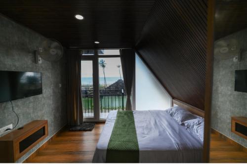 a bedroom with a large bed and a large window at Nirvana-Vadanappally Beach Villa in Irimbranallūr
