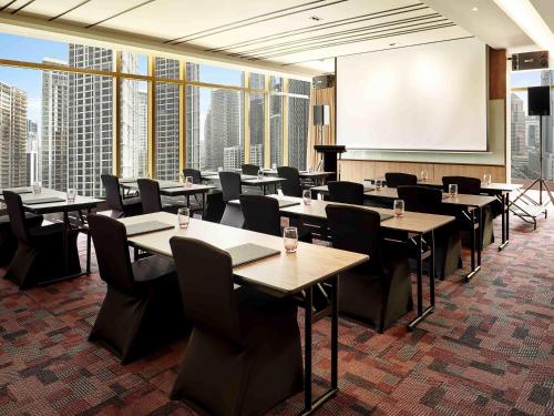 a conference room with tables and chairs and a projection screen at ibis Kuala Lumpur City Centre in Kuala Lumpur