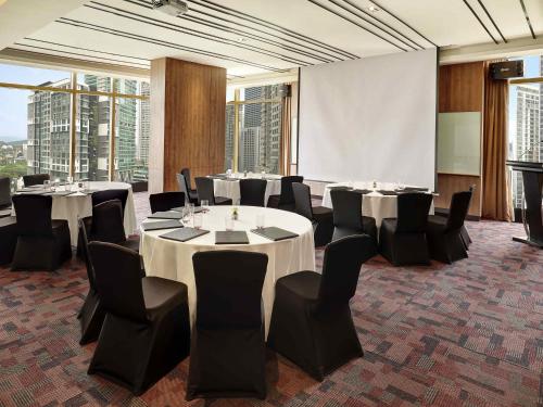a conference room with tables and chairs and a projection screen at ibis Kuala Lumpur City Centre in Kuala Lumpur