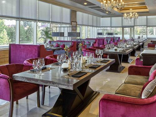 a dining room with long tables and purple chairs at Rixos President Hotel Astana in Astana