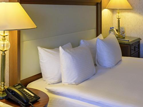 a hotel room with a bed with white pillows and a phone at Rixos President Hotel Astana in Astana