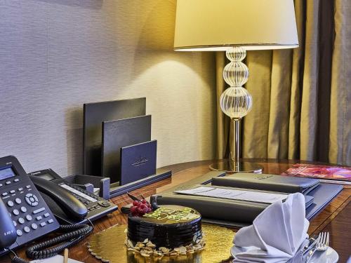 a desk with a phone and a cake on a table at Rixos President Hotel Astana in Astana
