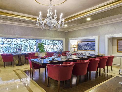 a dining room with a long table and red chairs at Rixos President Hotel Astana in Astana