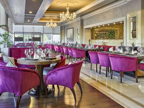 a restaurant with purple chairs and tables and a bar at Rixos President Hotel Astana in Astana