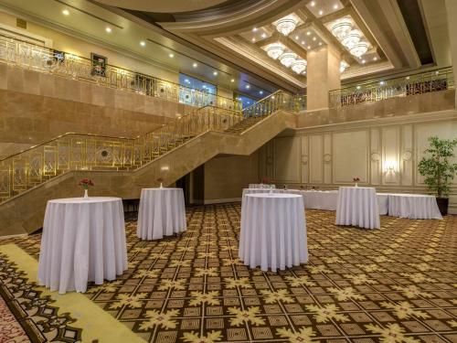 a banquet hall with two tables and a staircase at Rixos President Hotel Astana in Astana