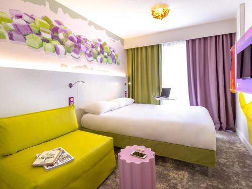 a hotel room with a bed and a couch at ibis Styles Fréjus St Raphael in Fréjus