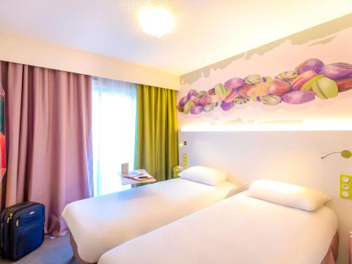 two beds in a hotel room with fruit on the wall at ibis Styles Fréjus St Raphael in Fréjus
