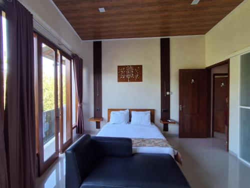 a bedroom with a bed and a couch and a window at L'JAVAS VILLAS in Kalibendo