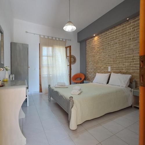 a bedroom with a large bed and a brick wall at Olga's Garden Apartments in Almiros Beach