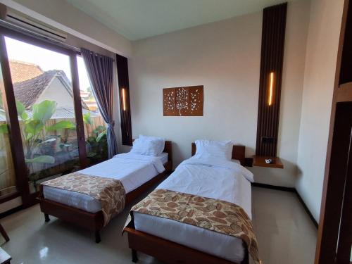 a hotel room with two beds and a window at L'JAVAS VILLAS in Kalibendo