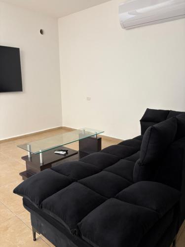 a black couch in a living room with a glass table at תכלת במושבה in Migdal